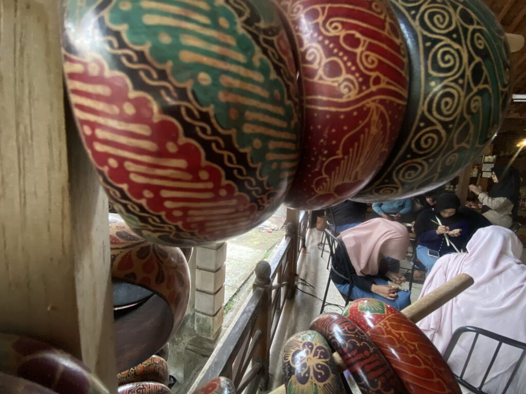 IMG_7416 - Mabur.co Close-up of colorful, patterned decorative spheres with gold swirls, displayed on a wooden rack indoors.