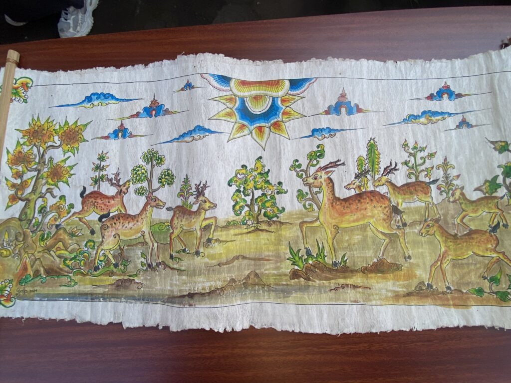 Colorful painted banner showing a forest scene with many deer and a large decorative sun at center-right.