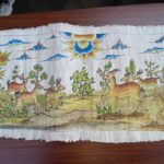 Colorful painted banner showing a forest scene with many deer and a large decorative sun at center-right.