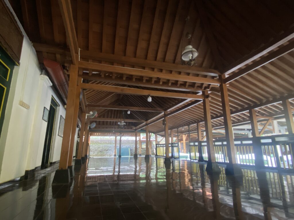 IMG_7776 - Mabur.co Inside a large hall with dark wooden ceiling beams, exposed trusses, and a glossy tiled floor; the space is empty apart from columns at intervals.