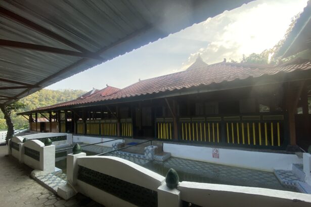 Covered outdoor walkway beside a red-tiled roof building with yellow and black railing, under a metal canopy.