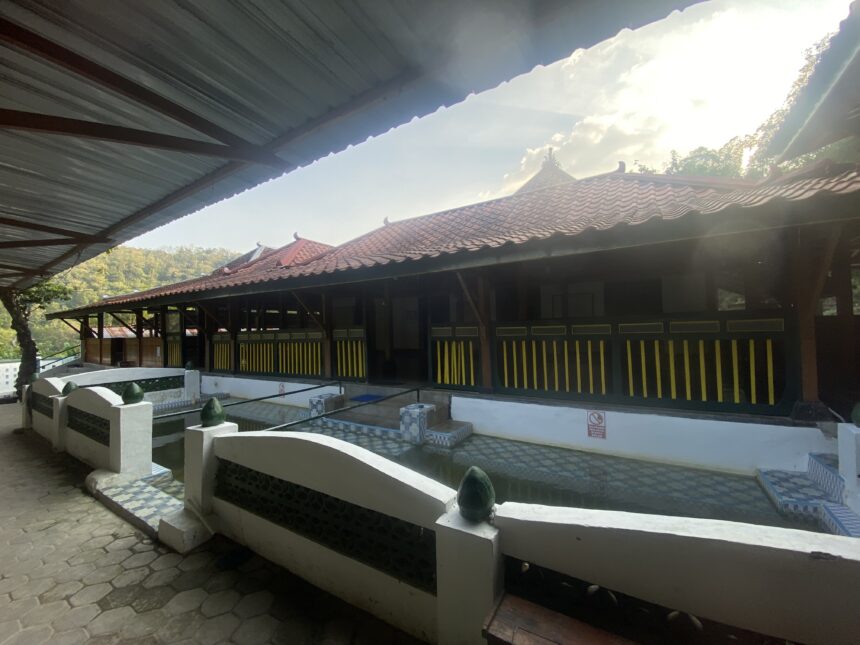 IMG_7782 - Mabur.co Covered outdoor walkway beside a red-tiled roof building with yellow and black railing, under a metal canopy.