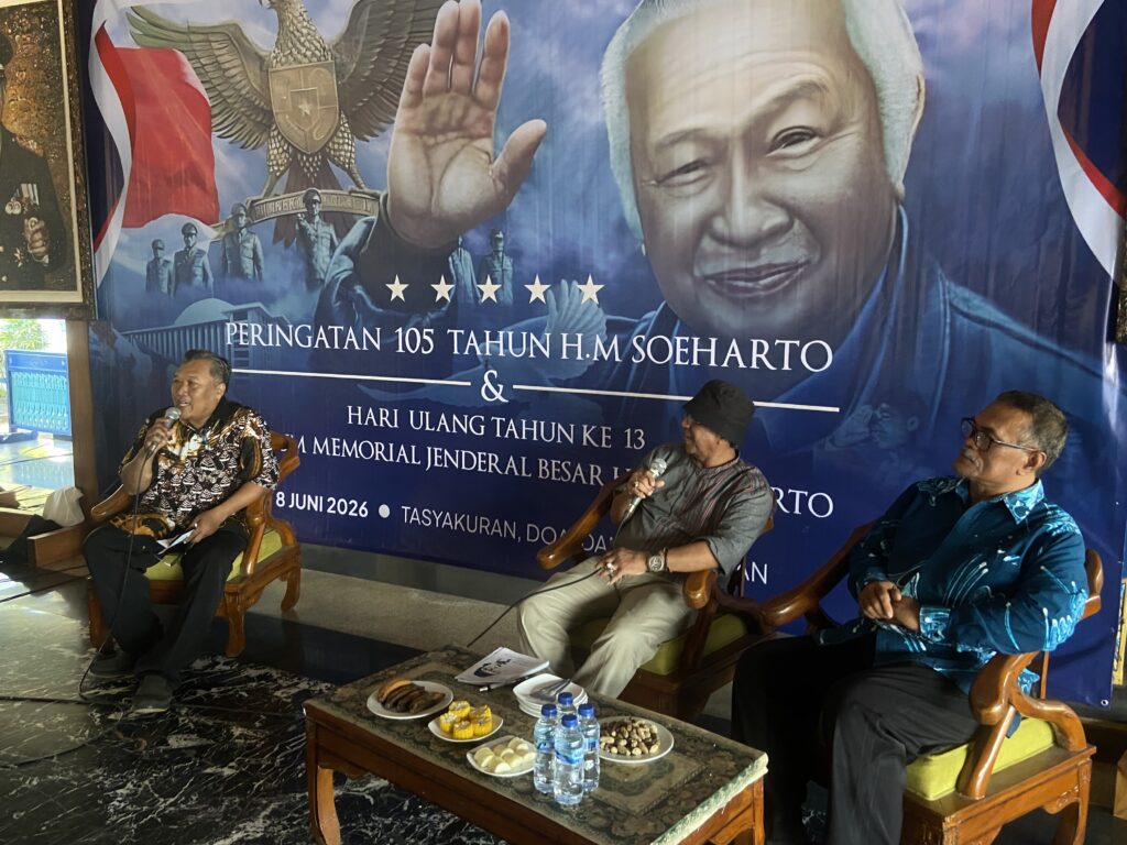 IMG_8053 - Mabur.co Panel discussion with three men holding microphones in front of a large banner featuring a portrait of Soeharto and Indonesian symbols.
