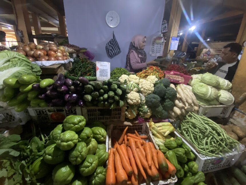 IMG_8144 - Mabur.co Night market vegetable stall with colorful produce like carrots, peppers, cauliflower, cabbage, and a vendor wearing a hijab in the background.