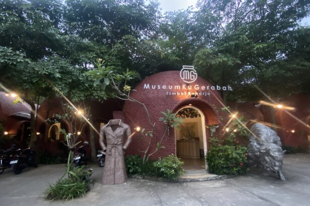 Entrance to a pottery museum with a red brick dome and a sign reading 'MuseumKugErabah Timbulharjo' amid trees and decorative lights