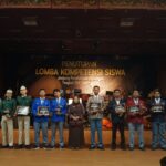 Group of students on stage receiving awards at the Lomba Kompetensi Siswa closing ceremony.