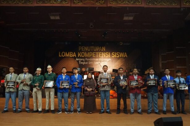 Group of students on stage receiving awards at the Lomba Kompetensi Siswa closing ceremony.
