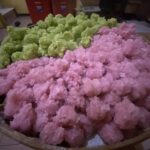 Pink and green fluffy snow-like dessert or candy heaped in a large bowl in a kitchen setting.