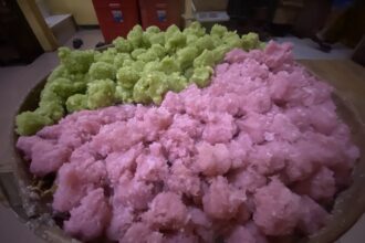 Pink and green fluffy snow-like dessert or candy heaped in a large bowl in a kitchen setting.