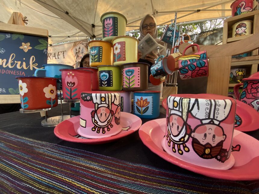 Colorful hand-painted mugs stacked on a market stall, featuring floral designs and bold colors.
