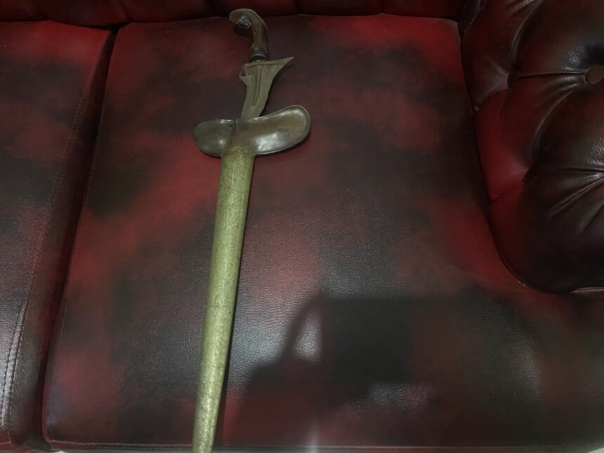 IMG_8727 - Mabur.co Antique curved dagger with ornate handle lying on a red leather sofa.