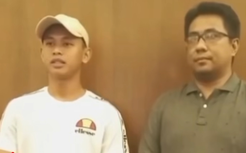 IMG_8811 - Mabur.co Two men stand indoors against a wooden wall; left is in a white cap and white shirt with a logo, right wears glasses and a green polo.