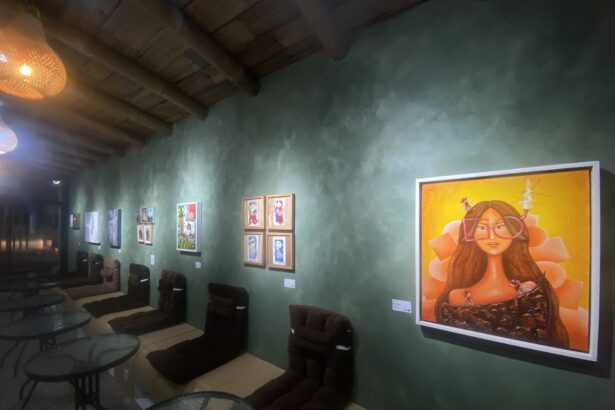 Gallery interior with green textured wall, wooden ceiling beams, and a large orange portrait on the right.