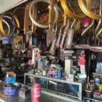Bicycle shop interior with numerous wheels and components hanging from the ceiling above a cluttered counter of parts and tools.