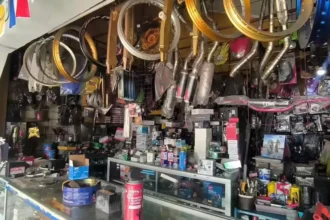 Bicycle shop interior with numerous wheels and components hanging from the ceiling above a cluttered counter of parts and tools.