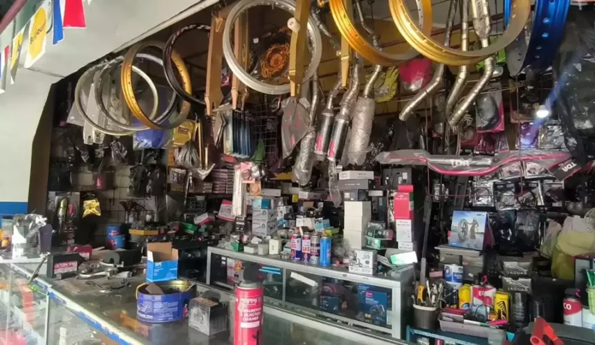 Bicycle shop interior with numerous wheels and components hanging from the ceiling above a cluttered counter of parts and tools.