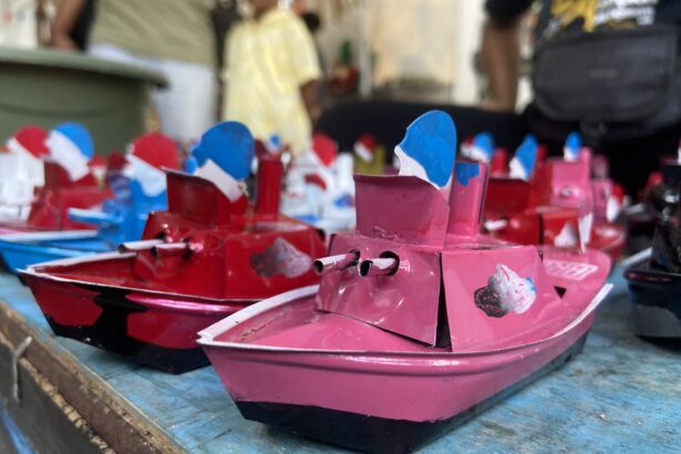 Close-up of colorful miniature pink and red toy boats with blue sails on a blue wooden surface