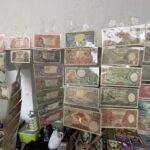 Display of Indonesian banknotes in plastic sleeves arranged on shelves, showing multiple colorful denominations of Rupiah.