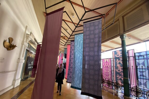 Indoor hallway with colorful patterned fabric banners suspended from a metal framework ceiling.