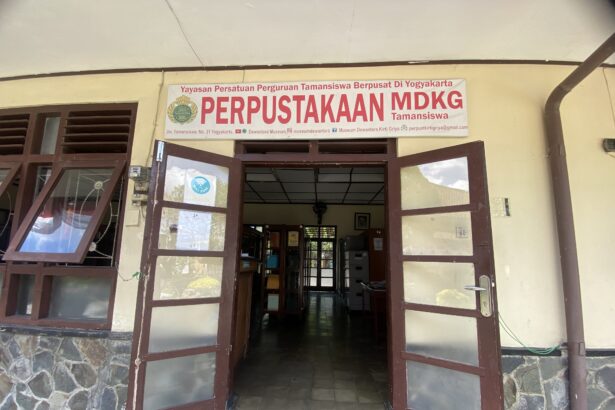 Open double doors to a library entrance with a large sign reading 'PERPUSTAKAAN MDKG Tamansiswa' above the doorway.