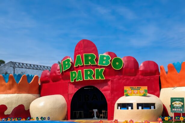 Colorful amusement park entrance with a large green 'IBARBO PARK' sign atop red archways and a flower-adorned path.