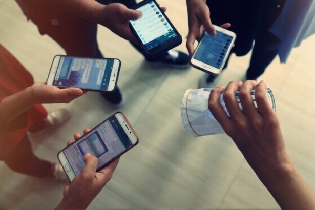 Top-down view of five people holding smartphones around a hand gripping a crumpled white paper bag on a light floor, implying a mobile payment or exchange.