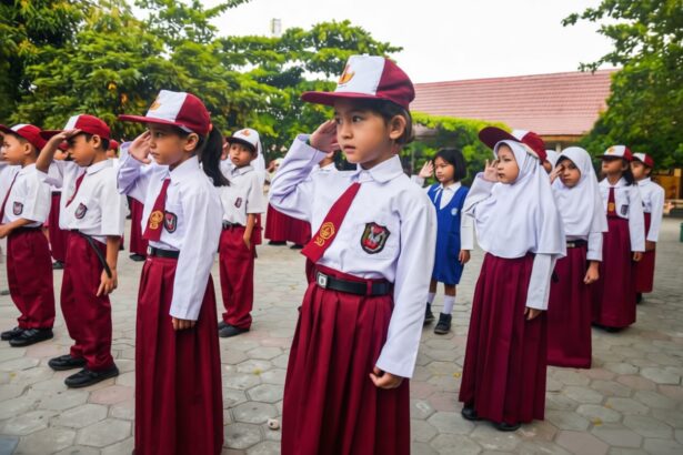 Group of young students in maroon skirts and white shirts, saluting during a school ceremony outdoors.