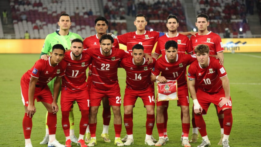Soccer team in red jerseys posing for a pre-match photo on the field, one player holds a pennant.