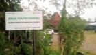 Large outdoor sign reading 'JOGJA YOUTH FARMING' with logos, surrounded by green plants and trees; a building with a red-tiled roof visible in the background