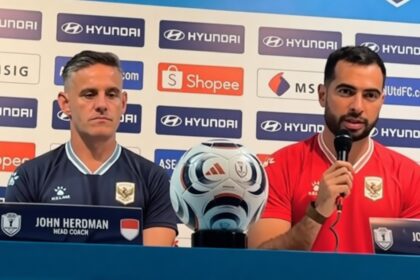 Press conference with head coach John Herdman (left) and player Jordi Amat (right) beside a soccer ball, sponsor backdrop.