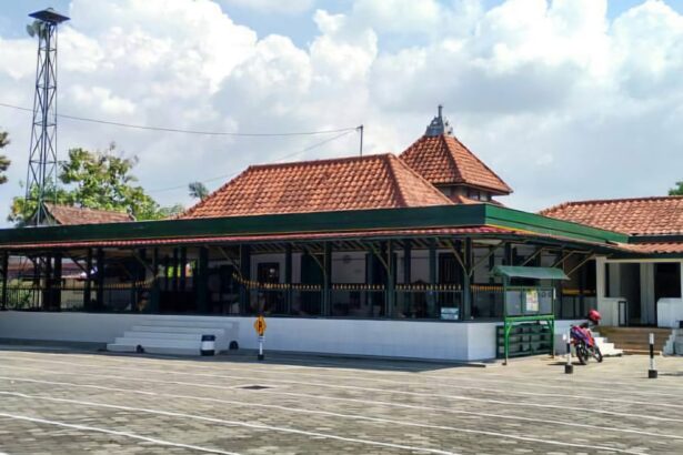Temple-style building with red tiled roofs and white walls in a paved open area; a motorcycle parked on the right side.
