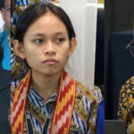 Triptych of panelists: left woman speaks into a microphone with yellow flowers on the table; center young woman with a colorful scarf; right man with glasses wearing a batik shirt speaking into a mic.