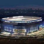 Aerial view of MetLife Stadium at dusk with the New York City skyline in the distance.