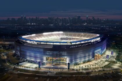 Aerial view of MetLife Stadium at dusk with the New York City skyline in the distance.
