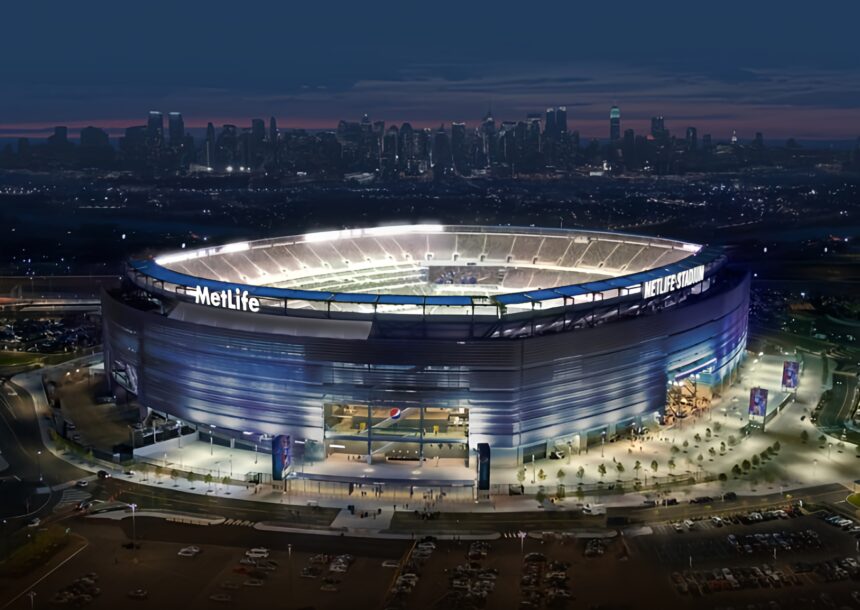 MetLife_Giants-Vertical-1 - Mabur.co Aerial view of MetLife Stadium at dusk with the New York City skyline in the distance.