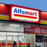 Alfamart storefront with red-yellow signage at dusk and a 5G Wi‑Fi banner outside ( Indonesia )