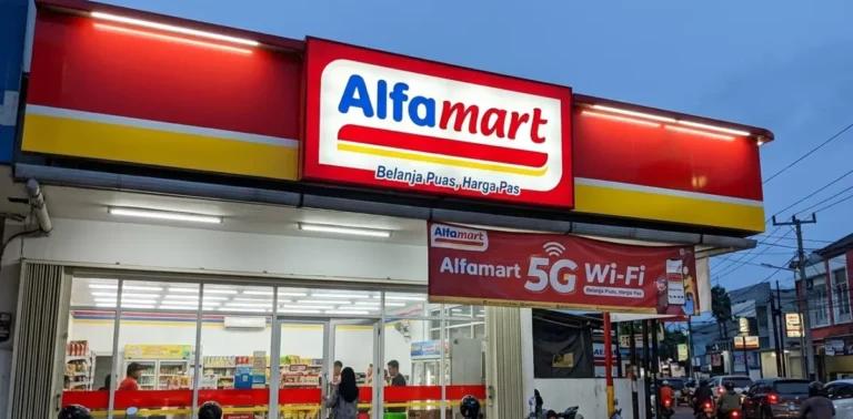 Alfamart storefront with red-yellow signage at dusk and a 5G Wi‑Fi banner outside ( Indonesia )