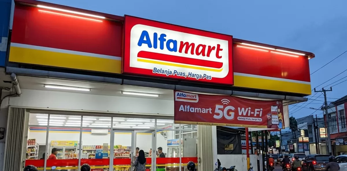 Alfamart storefront with red-yellow signage at dusk and a 5G Wi‑Fi banner outside ( Indonesia )