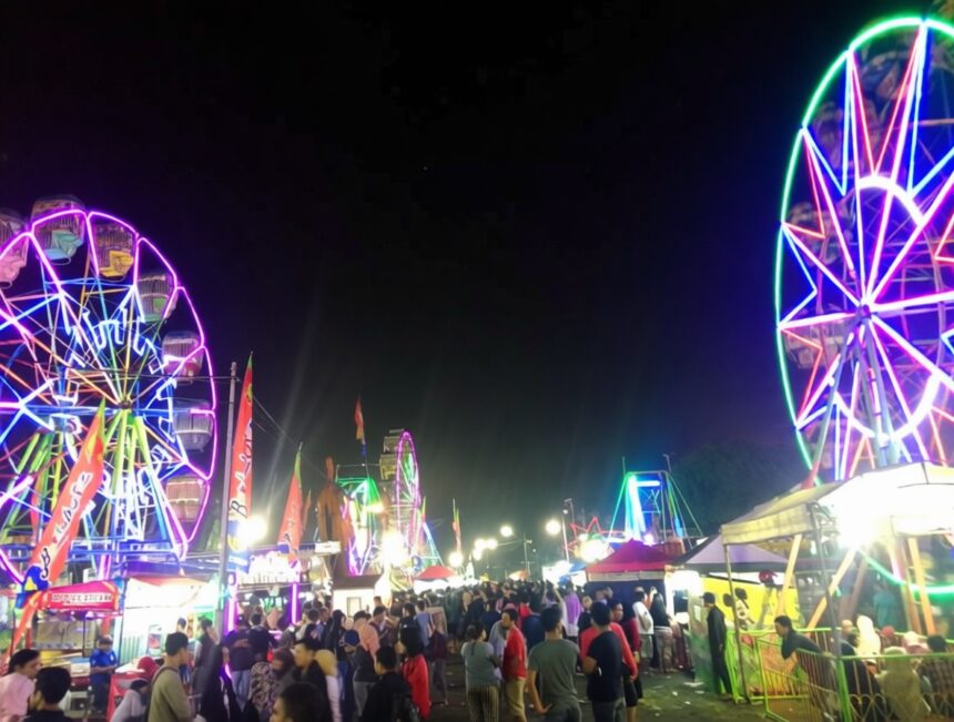Night carnival scene with colorful neon Ferris wheels and a crowded fairground at dusk/darkness