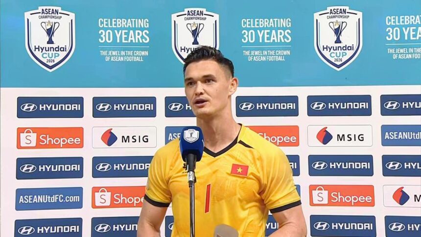 Vietnamese footballer in a yellow jersey speaks into a microphone at a press conference, with sponsor banners and a turquoise backdrop displaying ASEAN/Hyundai Cup logos.