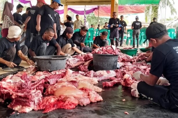 Group of volunteers in black shirts processing a large pile of raw meat under a tent. (informative)