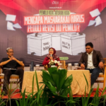 Panel discussion with three speakers on a stage; banner behind asks why society should care about electoral law revisions (Indonesian text).