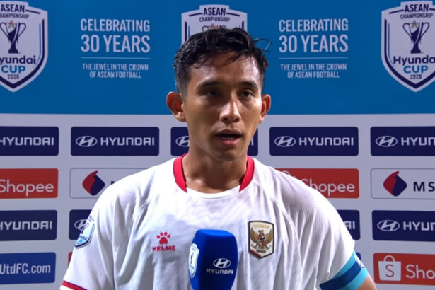 Footballer in white kit being interviewed with a blue Hyundai microphone, backdrop shows ASEAN Championship logos and sponsor banners.