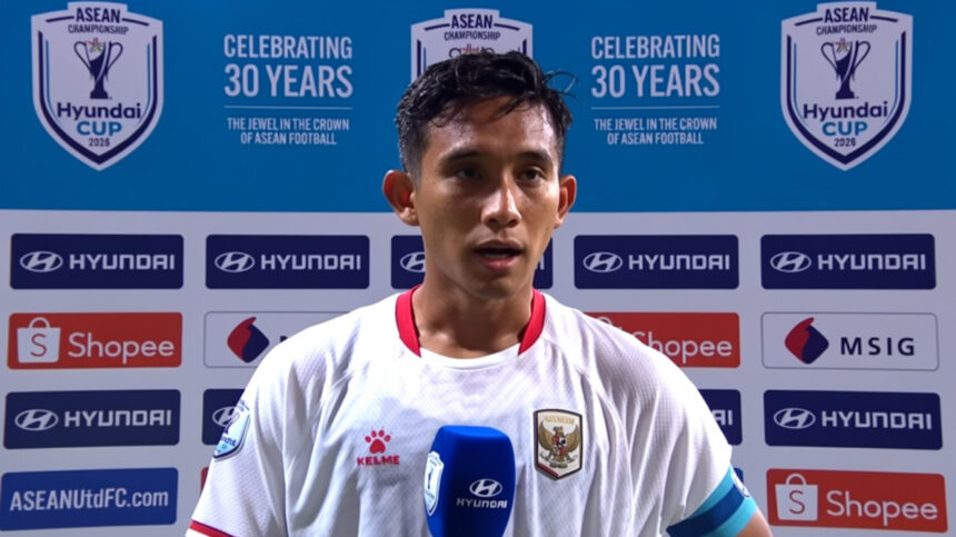 Footballer in white kit being interviewed with a blue Hyundai microphone, backdrop shows ASEAN Championship logos and sponsor banners.