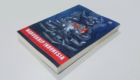 Paperback book titled Manuskrip Indonesia on a blue cover with a red title banner, resting on a white surface.