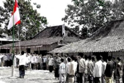 Crowd of villagers standing in a line during a flag-raising ceremony in a rural courtyard with traditional tiled-roof houses nearby.”] ,