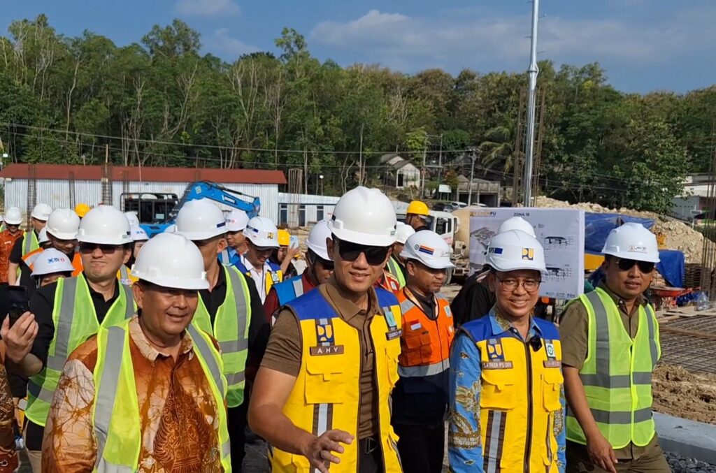Group of construction workers wearing white hard hats and bright safety vests at a construction site.