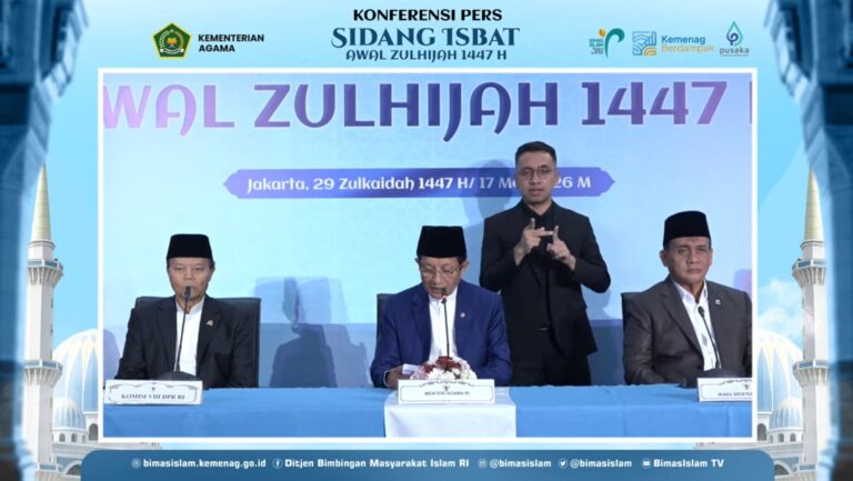 Four men sit at a conference table during a Kemenag press briefing for Sidang Isbat 1447 H, with a blue backdrop and Indonesian banners behind them.