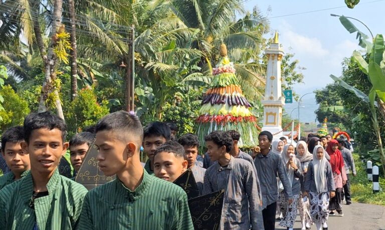 Parade with participants in green striped outfits walking along a palm-lined street, a colorful layered fruit tower behind them.