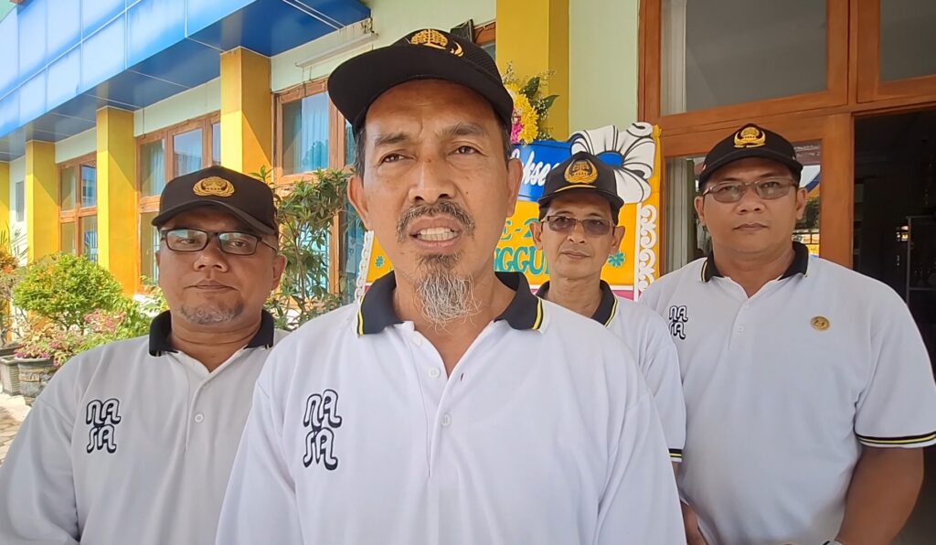 Screenshot_20260520_190144_Gallery - Mabur.co Group of four men in matching white polo shirts and black caps pose outside a colorful building with a blue awning.